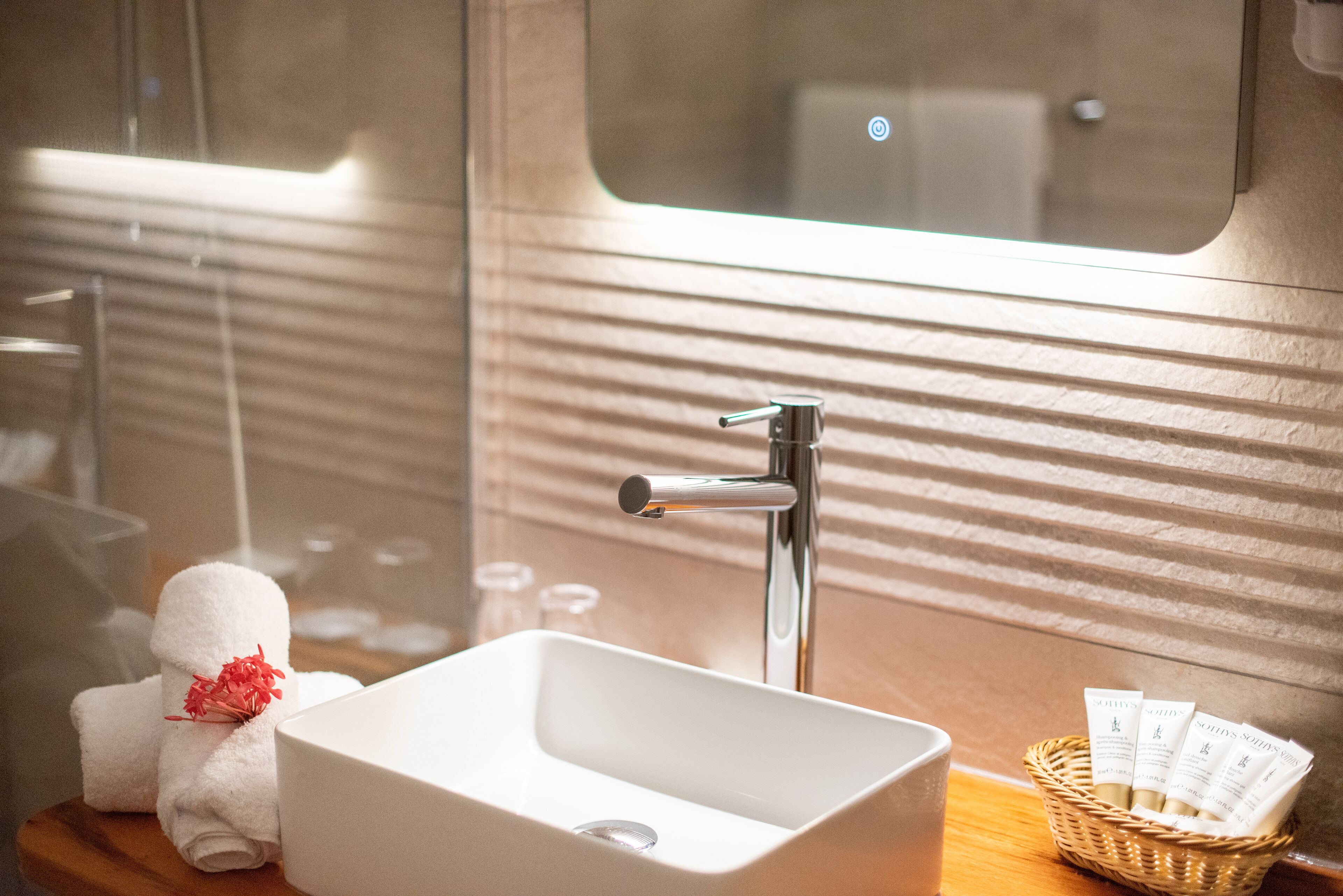 A bathroom with a white sink, a mirror, and a window.
