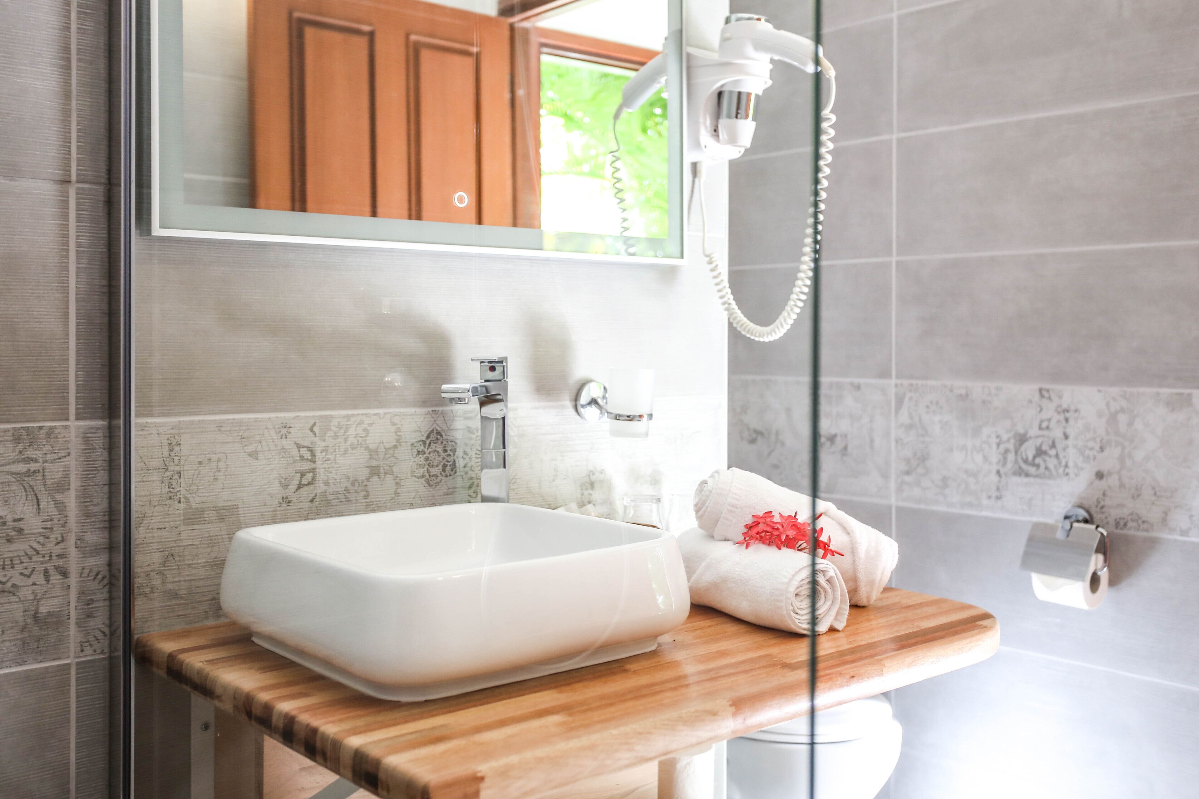 A modern bathroom with a large white sink, wooden countertop, and a glass shower enclosure.