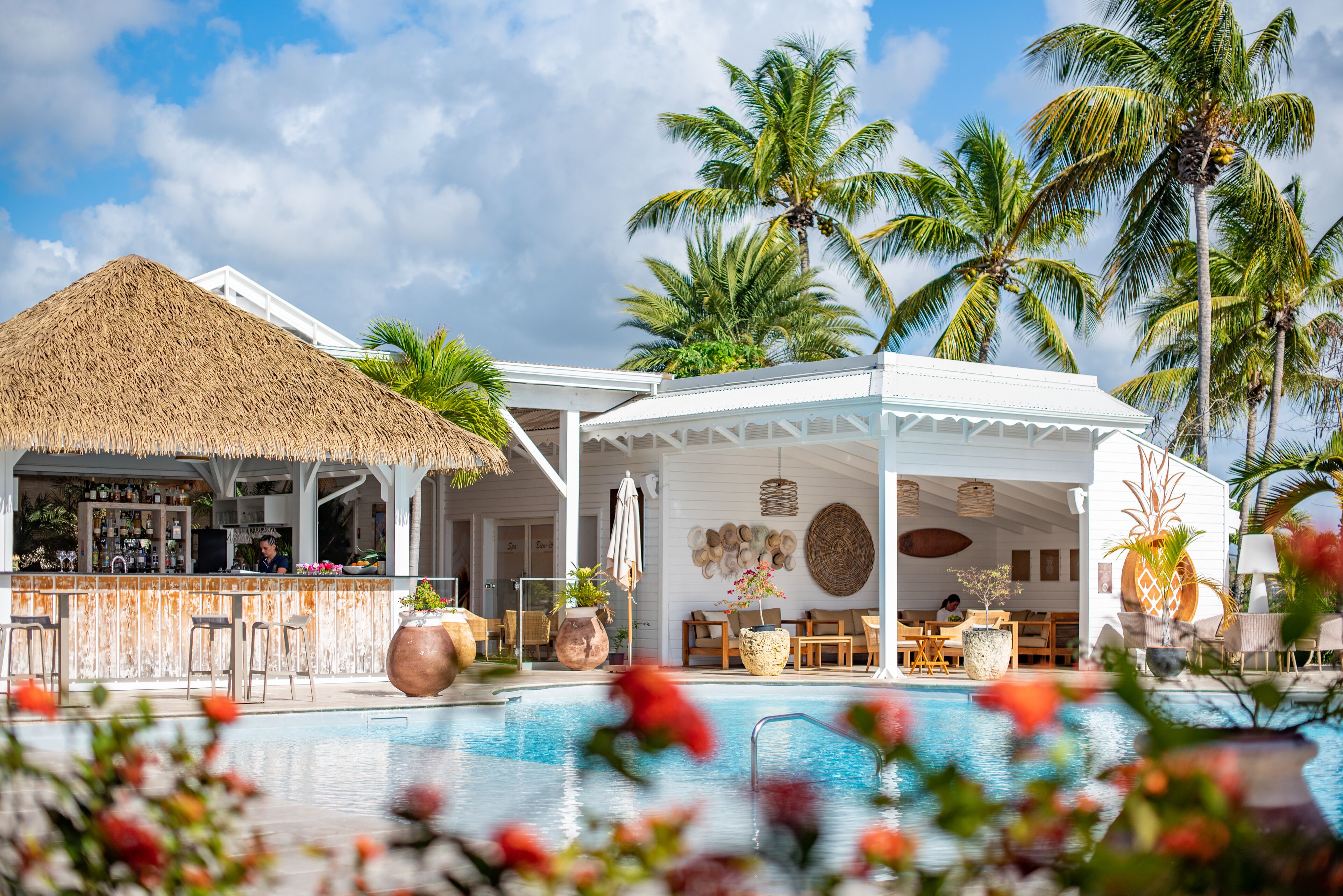 A resort with a pool, bar, and outdoor seating area surrounded by palm trees.