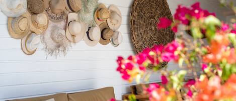 Una habitación con una fila de sombreros en la pared, una cesta tejida y un sofá con cojines.