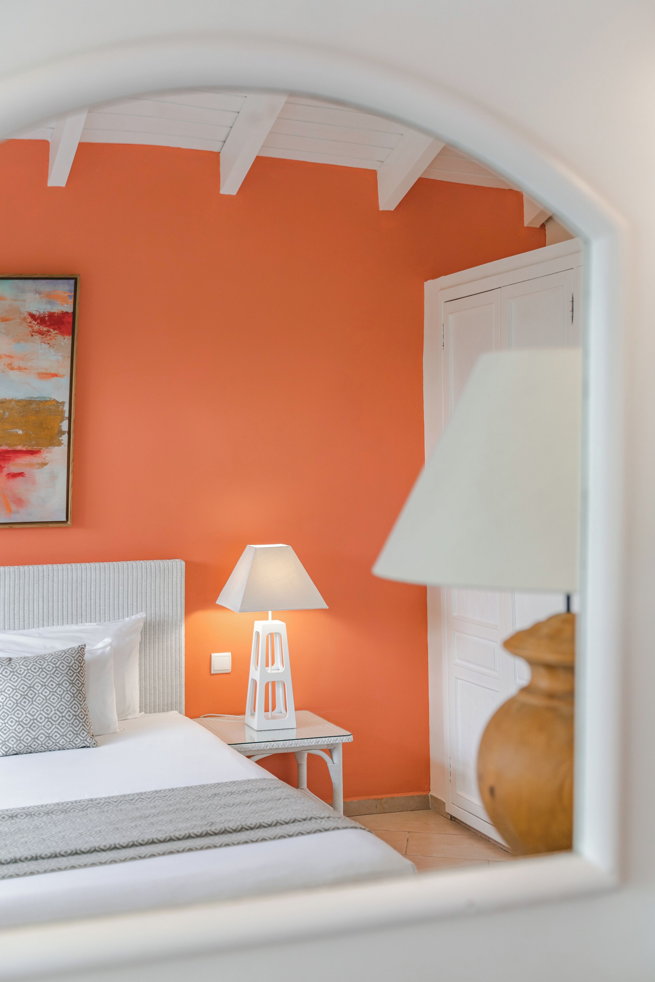 A hotel room with a bed, a bedside lamp, a small table, and a door.