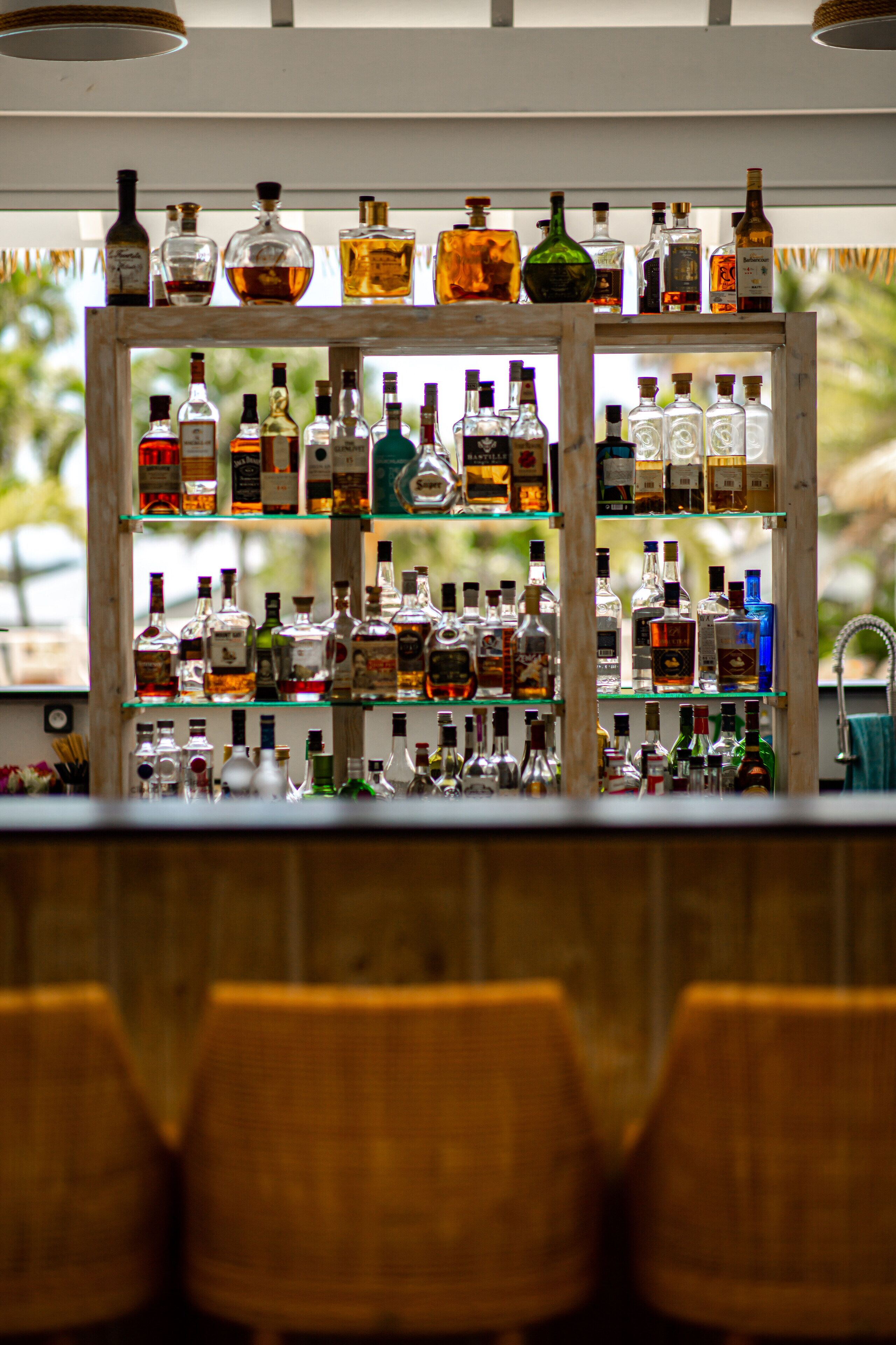A bar area with shelves of liquor bottles and wicker chairs.