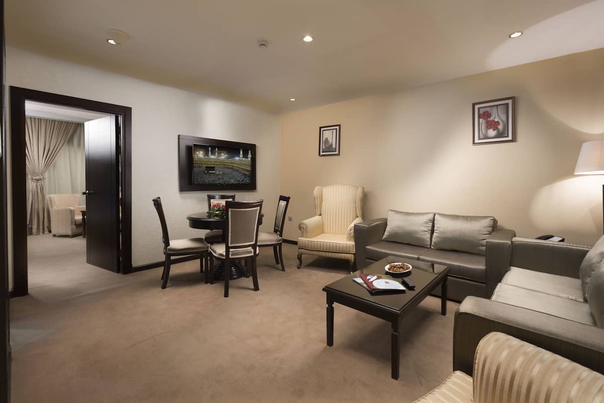 A modern living room with a sofa, armchairs, a coffee table, and a TV.