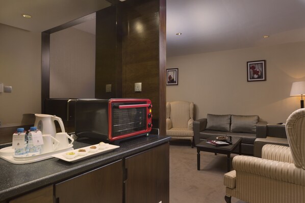 Habitación de hotel con kitchenette, sofá, silla y lámpara.