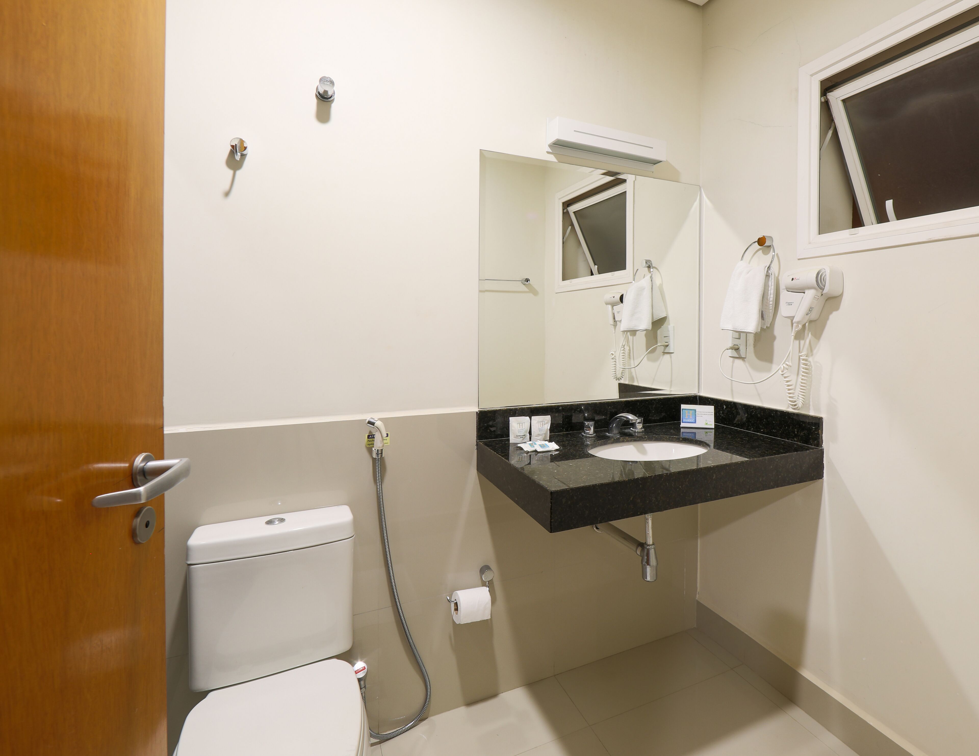 Un baño con inodoro, lavamanos y espejo.