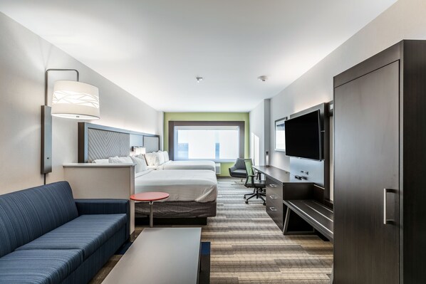 A modern hotel room with a bed, a sofa, a desk, a TV, and a large window.
