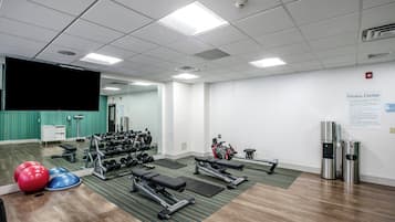 A fitness center with exercise equipment, a mirror, and a sign indicating the facility.