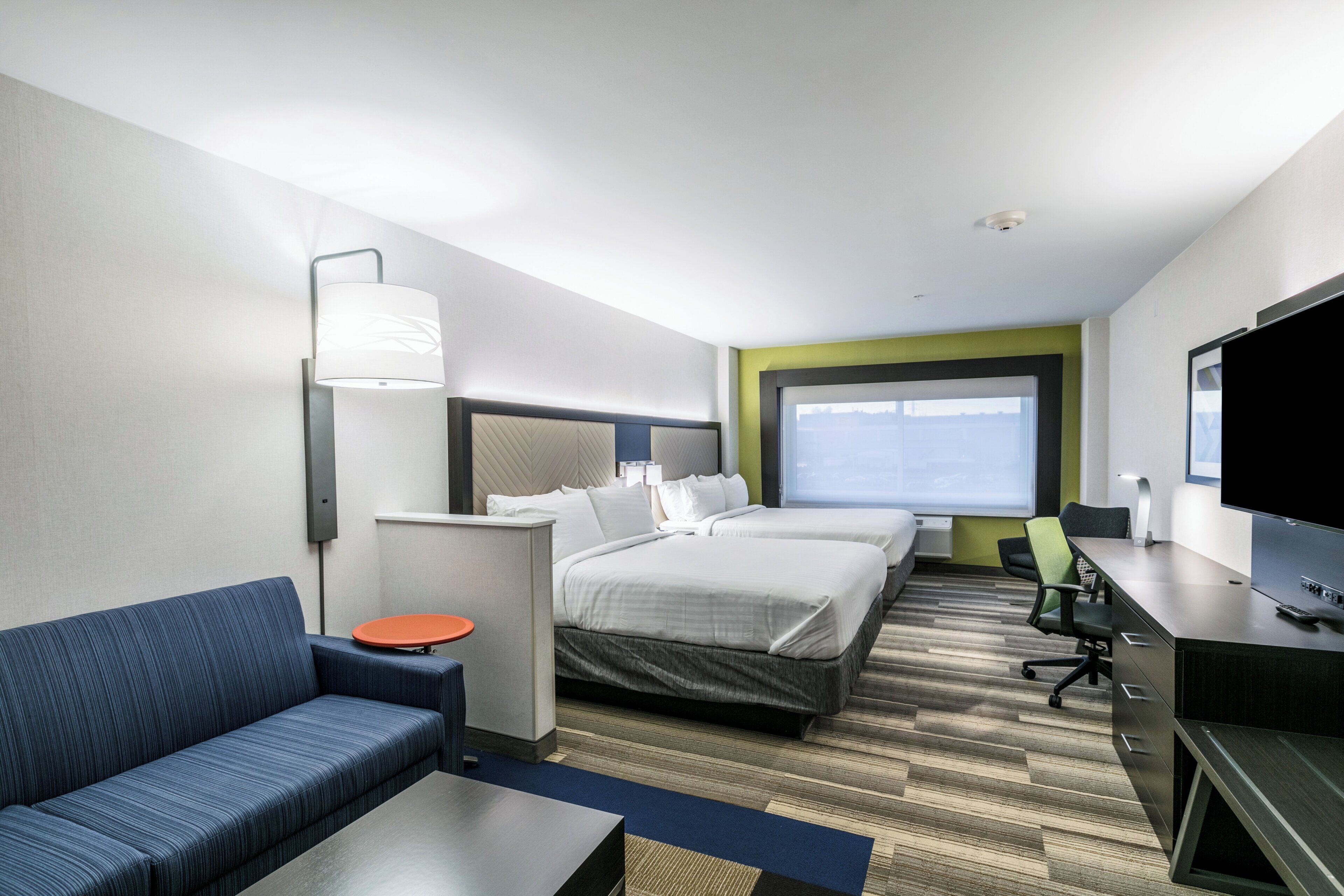 Une chambre d’hôtel avec un lit, un canapé, un bureau, une télévision et une fenêtre.