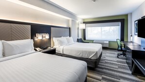 Hotellihuone, jossa on kaksi sänkyä, työpöytä, tuoli, televisio ja ikkuna, josta on näkymä.