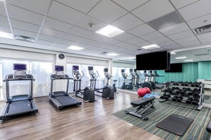 Een sportschool met loopbanden, elliptische trainers en losse gewichten.