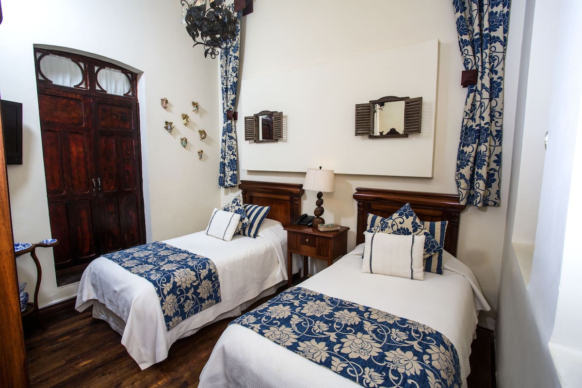 Une chambre d’hôtel avec deux lits, des têtes de lit en bois et un grand miroir au mur.
