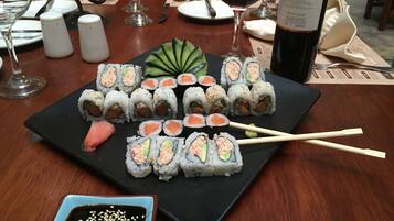 A sushi platter on a black plate with chopsticks and a small bowl of soy sauce.