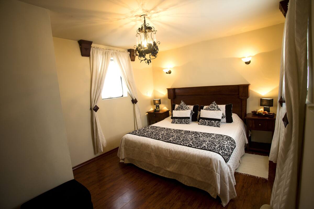 Une chambre à coucher avec un grand lit, une tête de lit en bois, des lampes de chevet et un lustre.