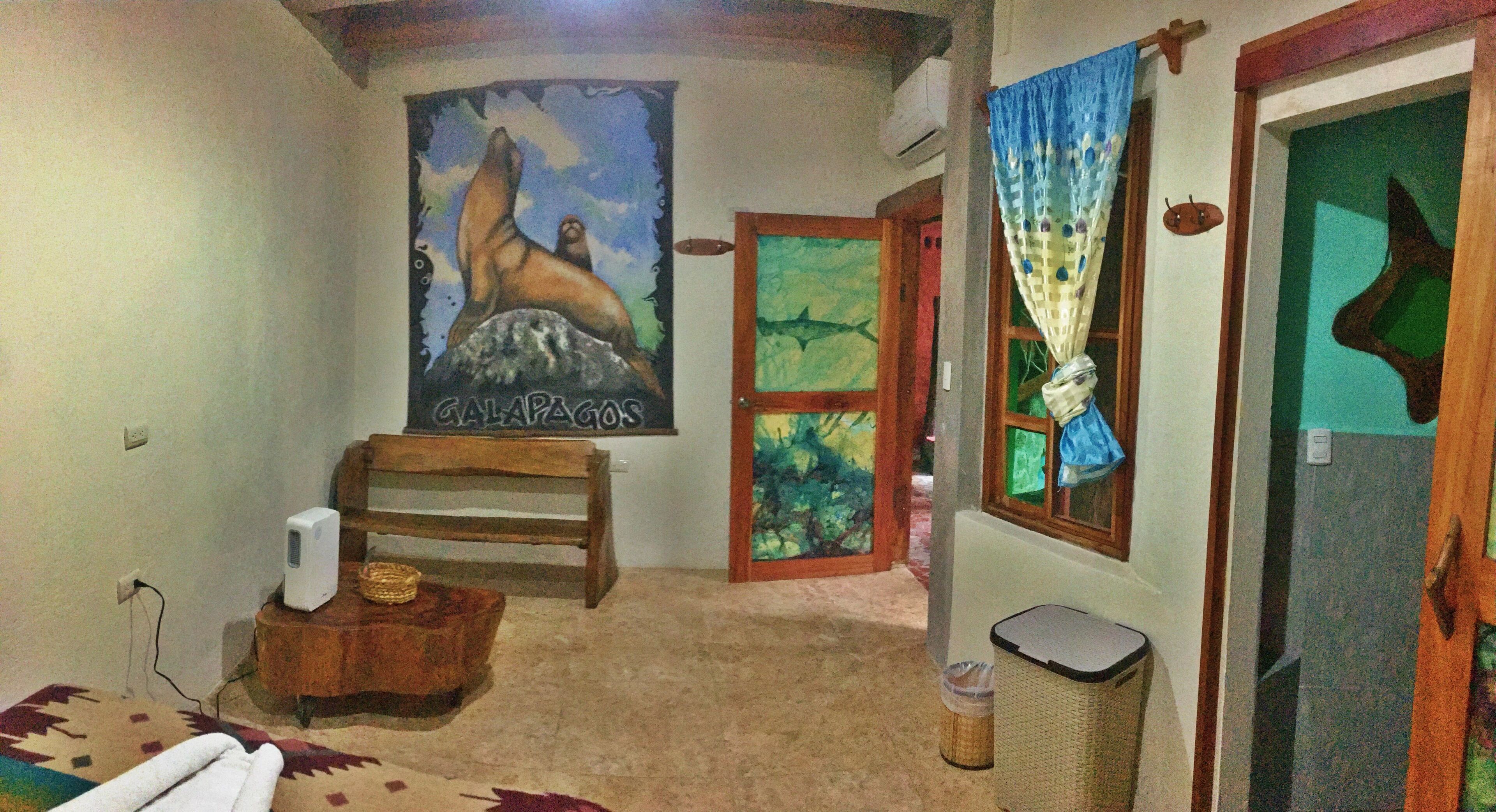 A room with a poster of a sea lion, a wooden bench, a small table with a basket, a trash bin, and a door with a curtain.