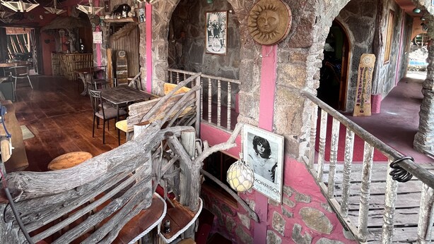 A rustic interior with a wooden ceiling, stone walls, and a mix of wooden and metal furniture. - Lonesome George Ecolodge (Puerto Ayora)