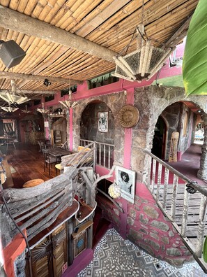A rustic interior with a wooden ceiling, stone walls, and a mix of wooden and metal furniture. - Lonesome George Ecolodge (Puerto Ayora)