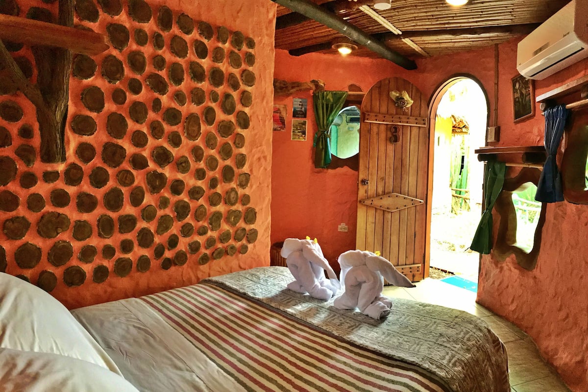 A room with a bed, a wooden door, and a wall with circular patterns.