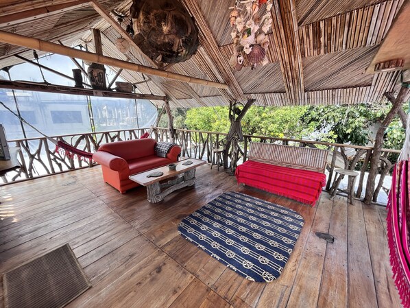 A wooden deck with a red sofa, a coffee table, and a patterned rug.