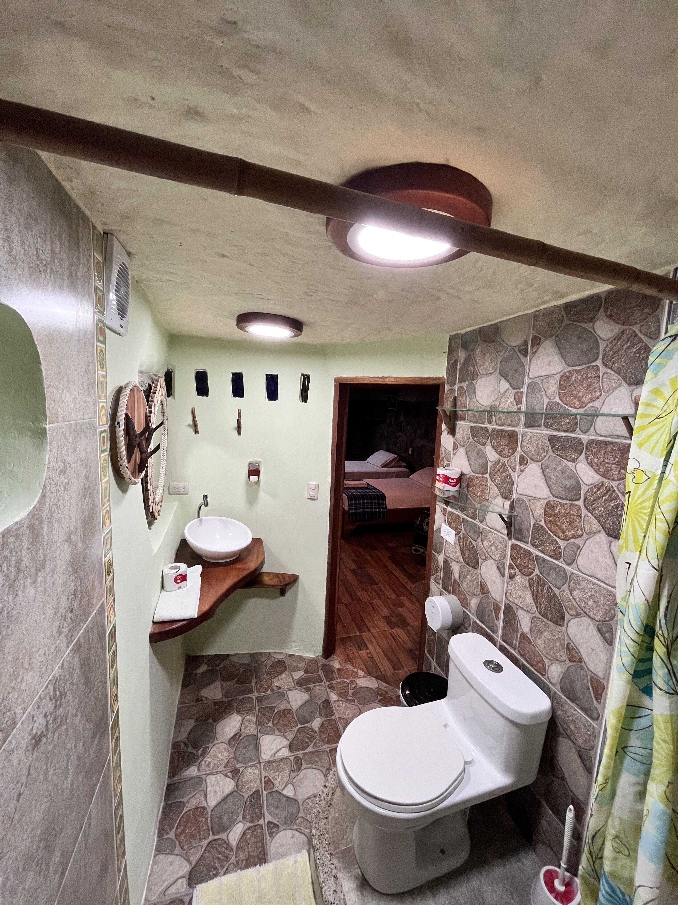 Et lille badeværelse med toilet, vask og bruseområde.