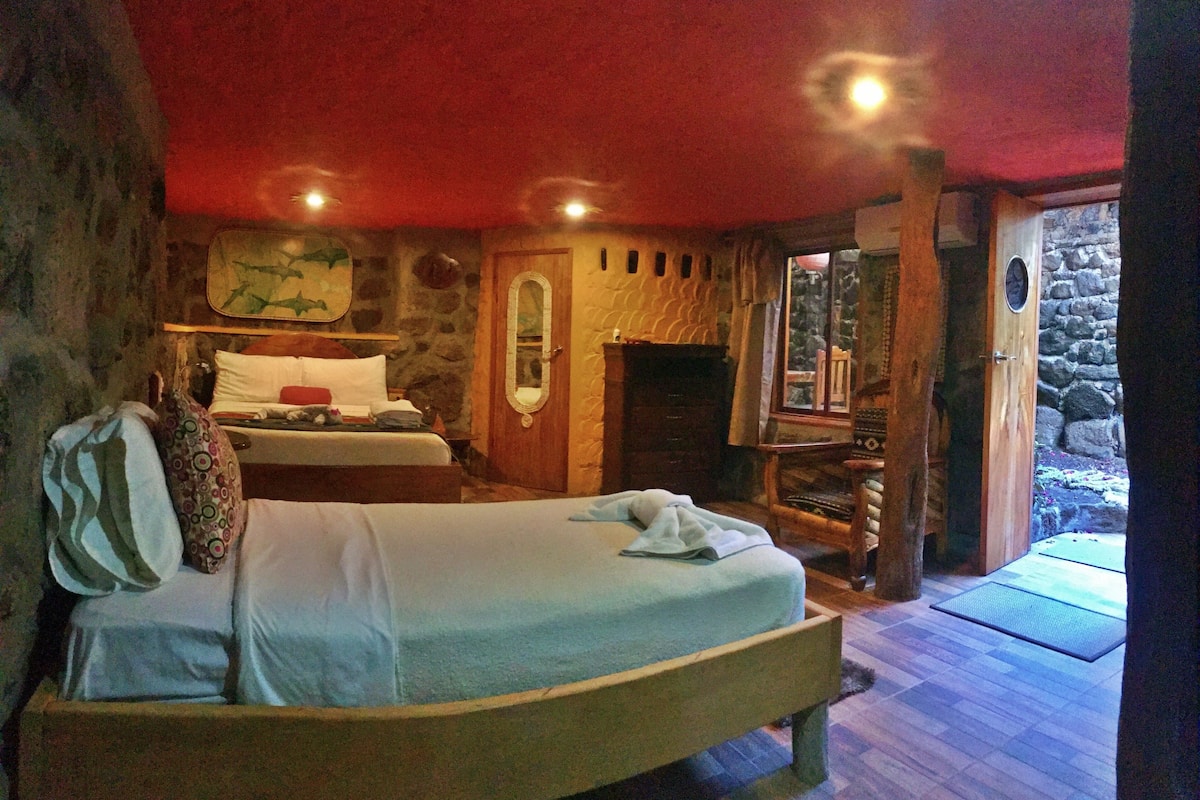 A cozy bedroom with a bed, a fireplace, and a stone wall.