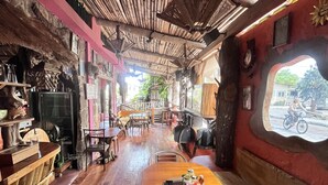 An interior with a wooden ceiling, tables, chairs, and a view through a window. - Lonesome George Ecolodge (Puerto Ayora)