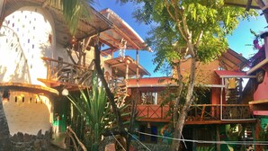 A rustic building with a tower, surrounded by palm trees and colorful architecture. - Lonesome George Ecolodge (Puerto Ayora)