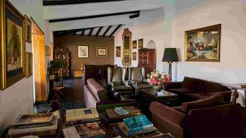 A cozy room with leather sofas, a coffee table, and a bookshelf filled with books.