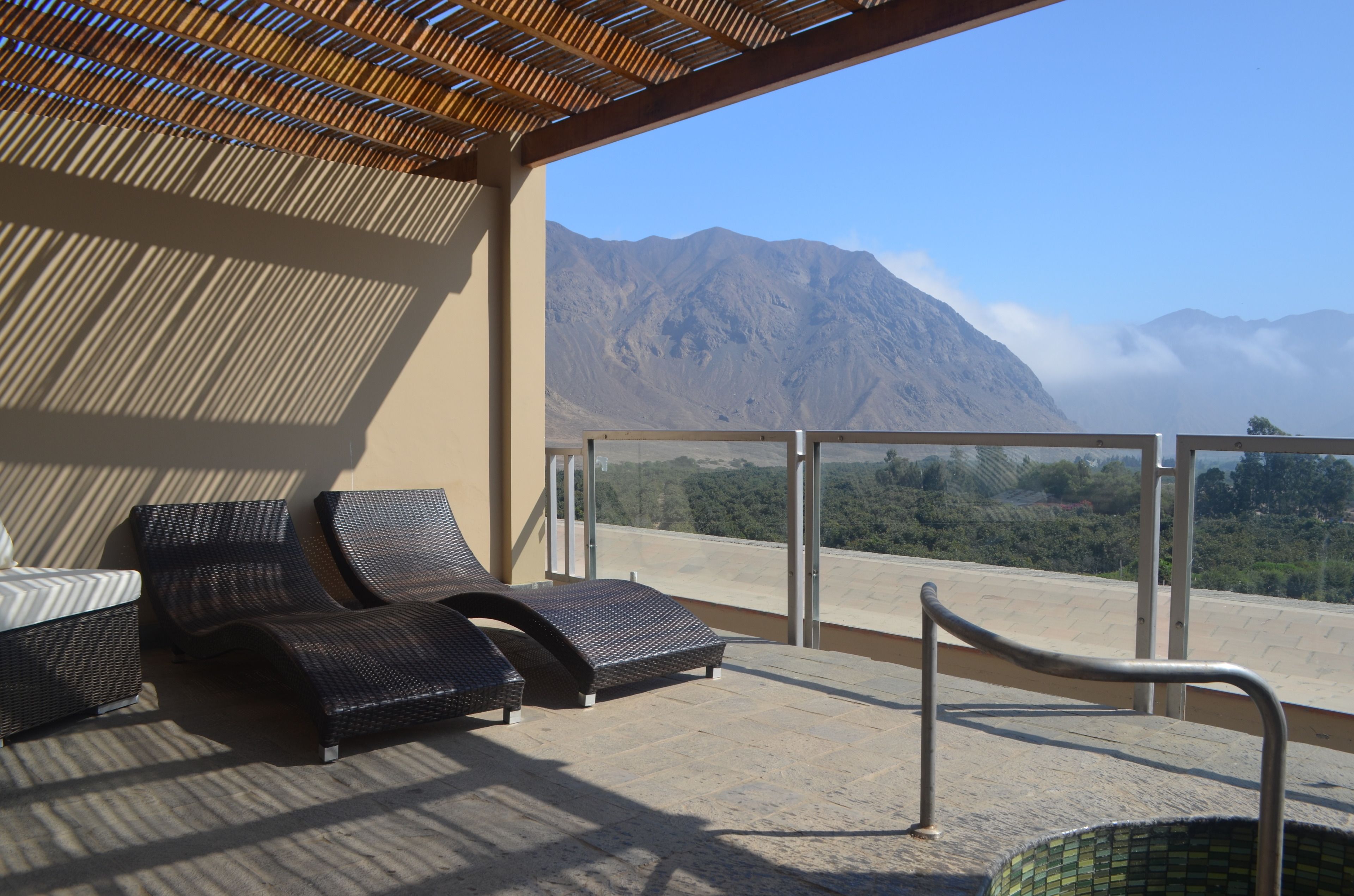 A balcony with wicker furniture and a view of mountains.