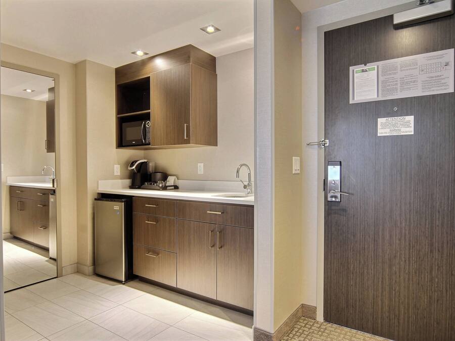 A modern kitchen with wooden cabinets, a built-in microwave, and a stainless steel refrigerator.