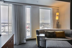 Enjoy a panoramic city view from the large window in this stylish room, featuring a comfortable sofa, desk, and floor lamp.