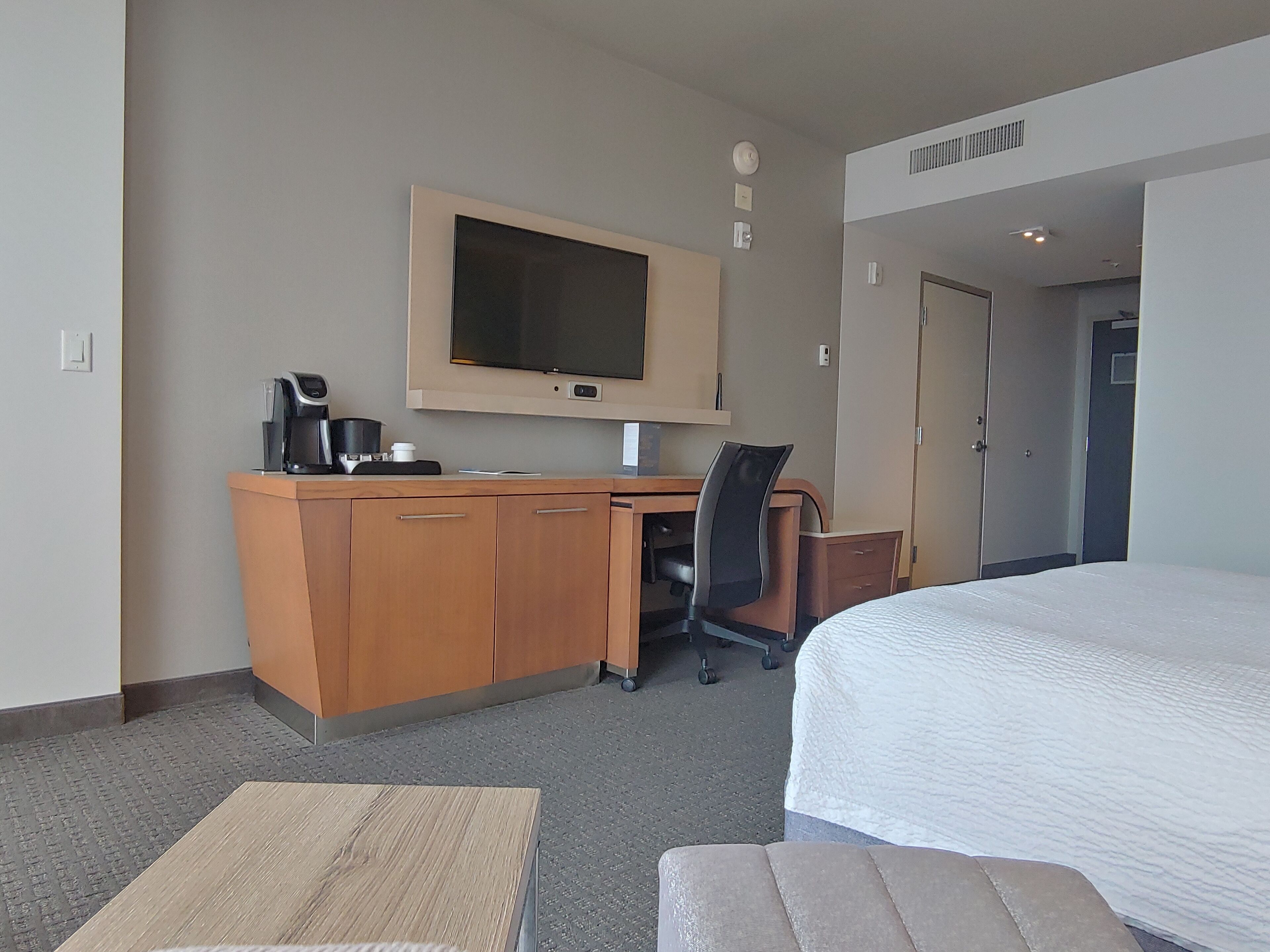 Une chambre d’hôtel équipée d’un lit, d’un bureau avec une chaise, d’une télévision et d’une machine à café.