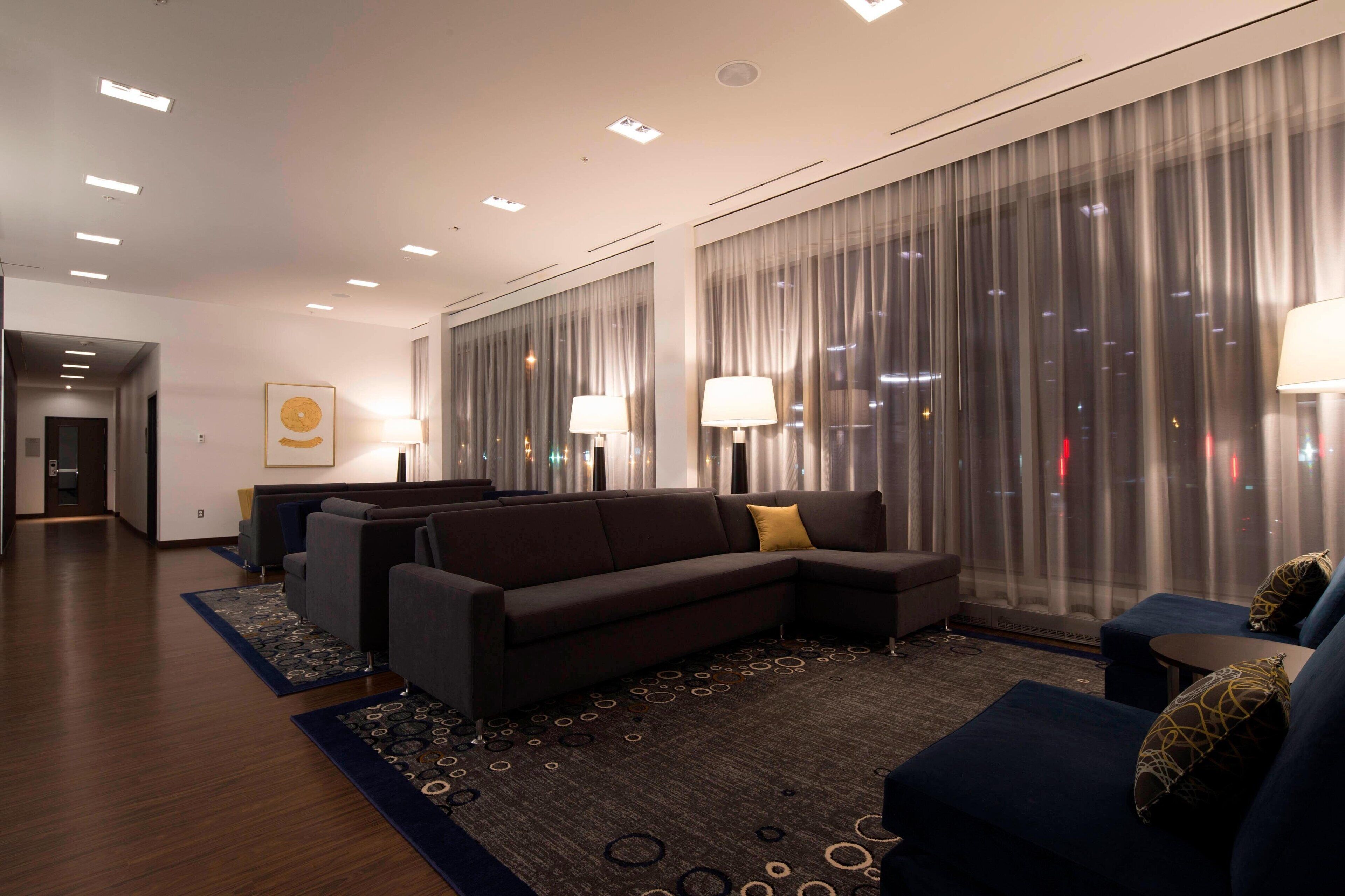 Un moderno vestíbulo de hotel con un sofá modular, una pequeña mesa redonda y una alfombra estampada.