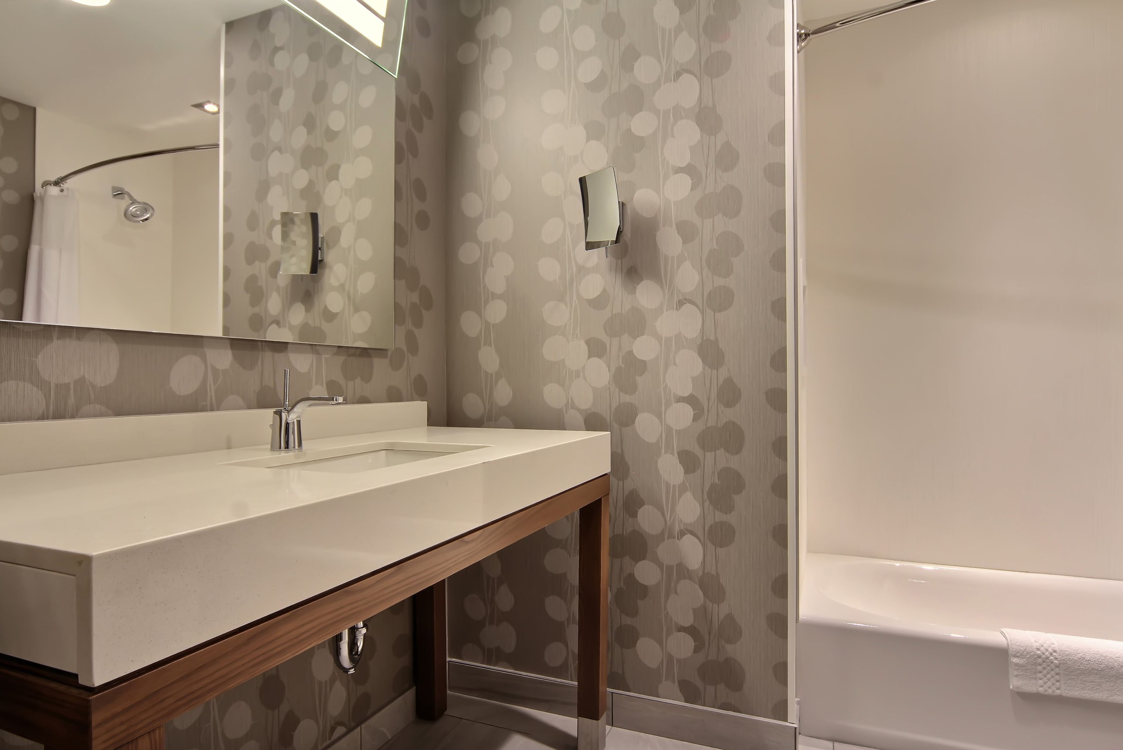 Un baño con tocador de madera, espejo, ducha e inodoro.