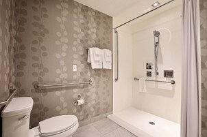 Une salle de bain équipée de toilettes, d’une douche avec une porte en verre et d’une barre d’appui.
