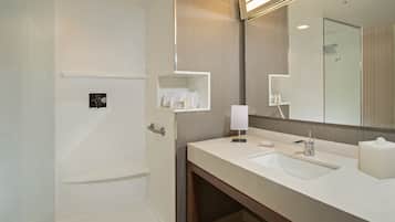 Une salle de bain moderne avec un grand miroir, deux lavabos et une douche.