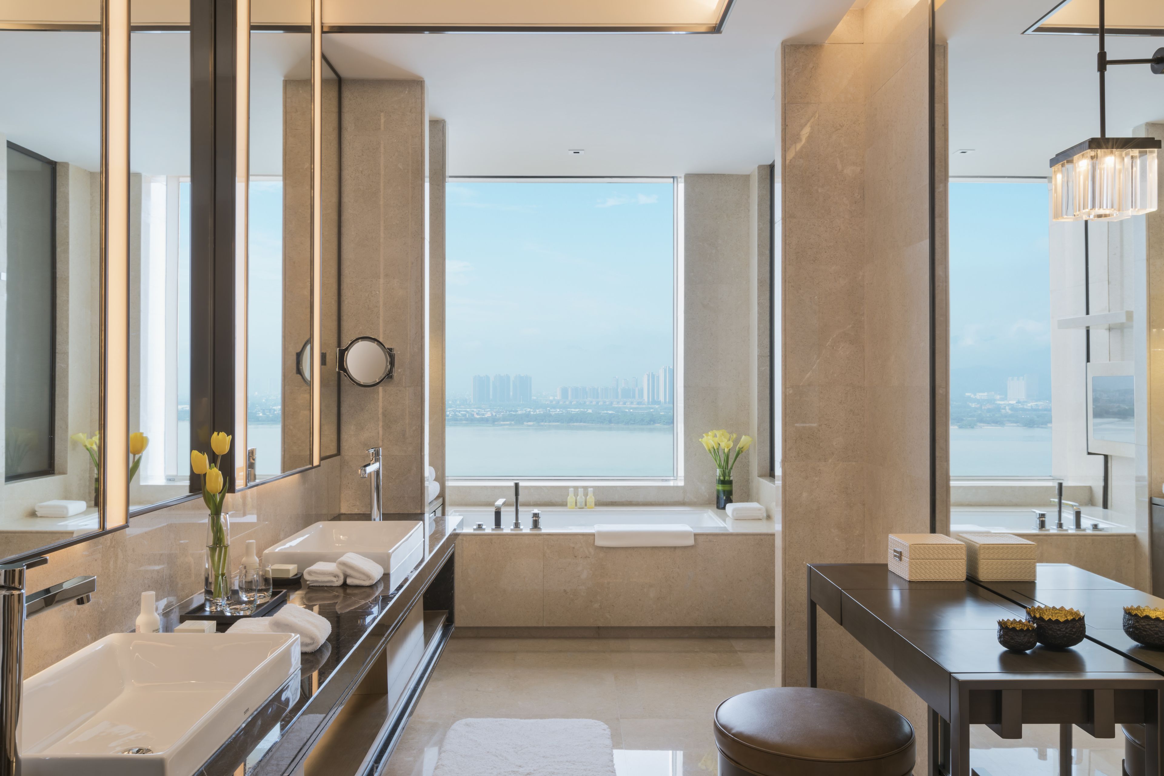 Ein modernes Badezimmer mit großem Fenster, einer Badewanne, einem Waschtisch mit Spiegel und einer Toilette.