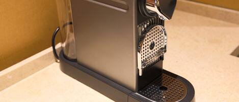 En kaffemaskin med en tydlig vattenbehållare, en droppuppsamlare och en kontrollpanel.
