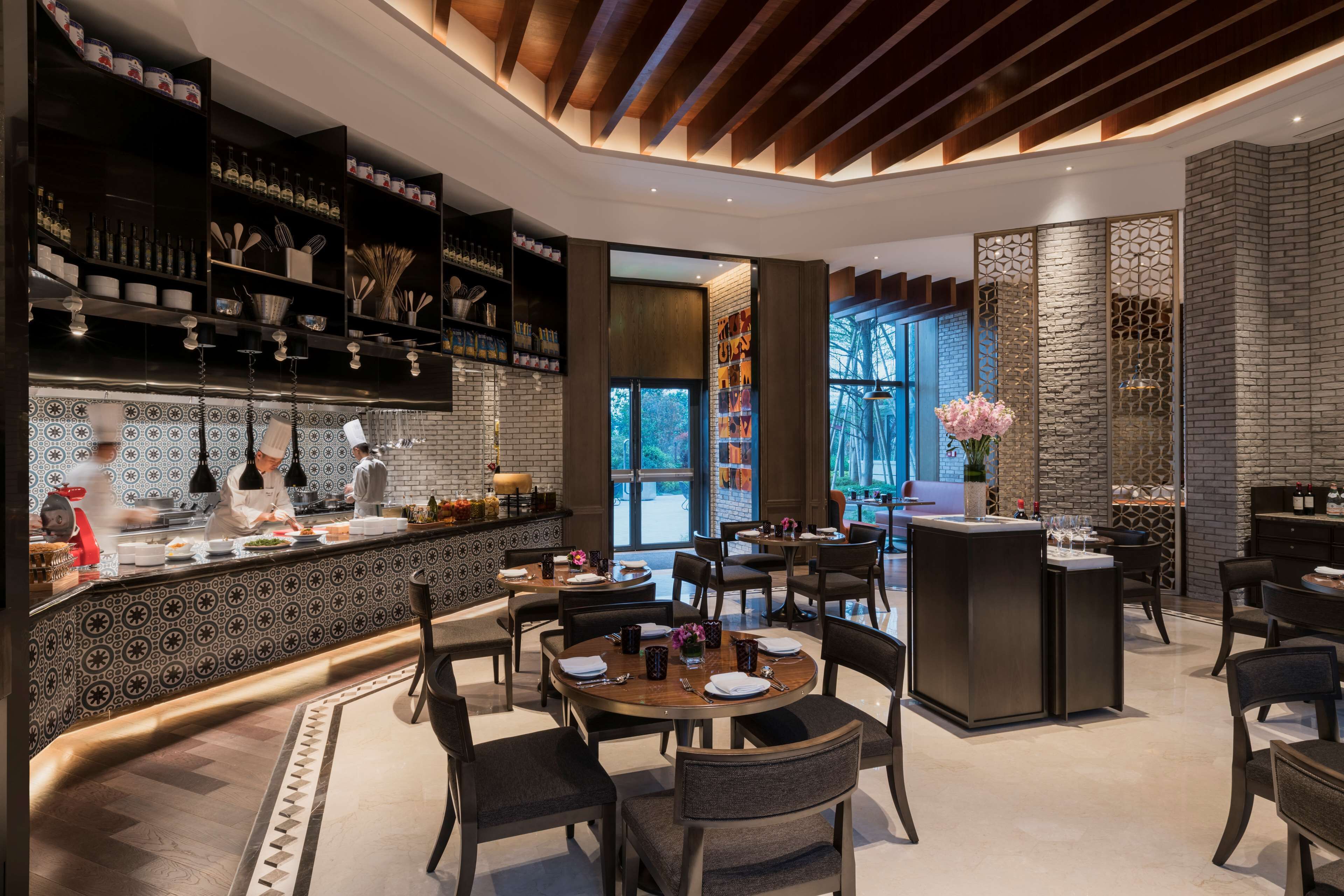 A modern restaurant with a central bar area, dining tables, and chairs.