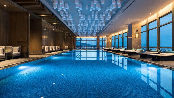 Una piscina interior moderna con vistas despejadas a las montañas al fondo.