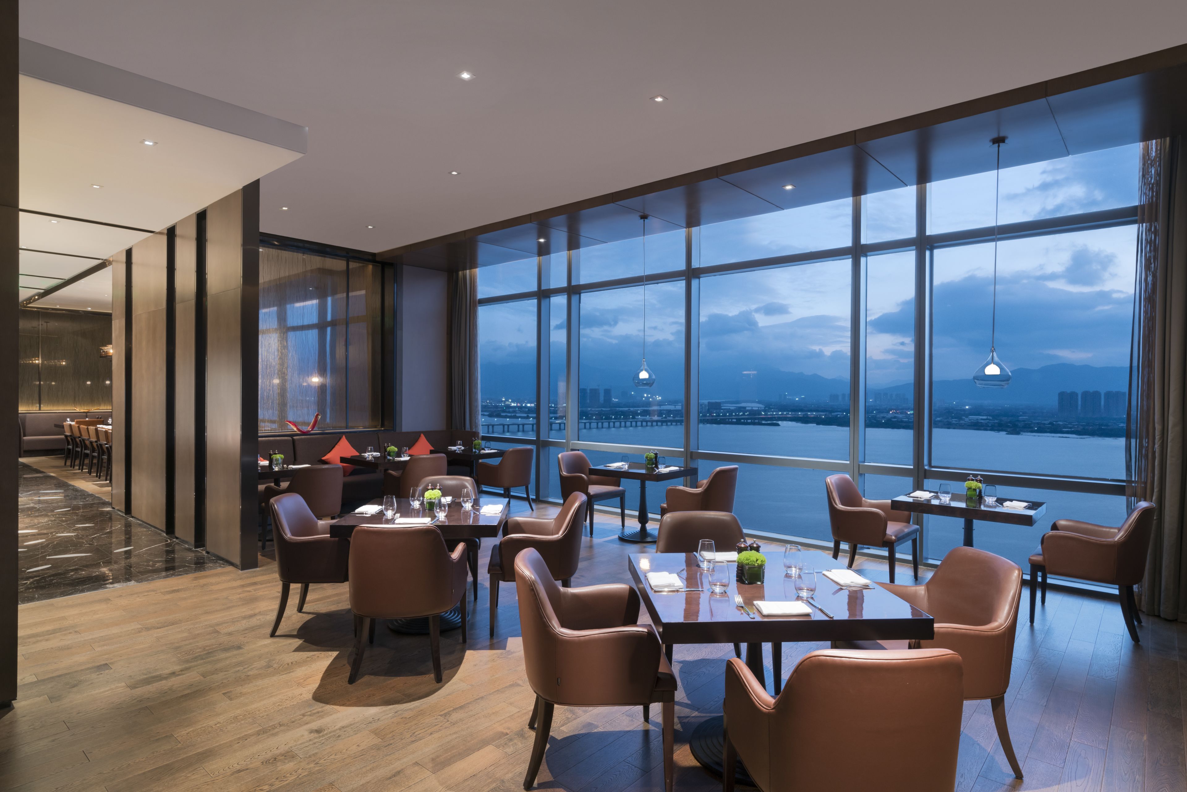 A modern restaurant with large windows offering a city view.
