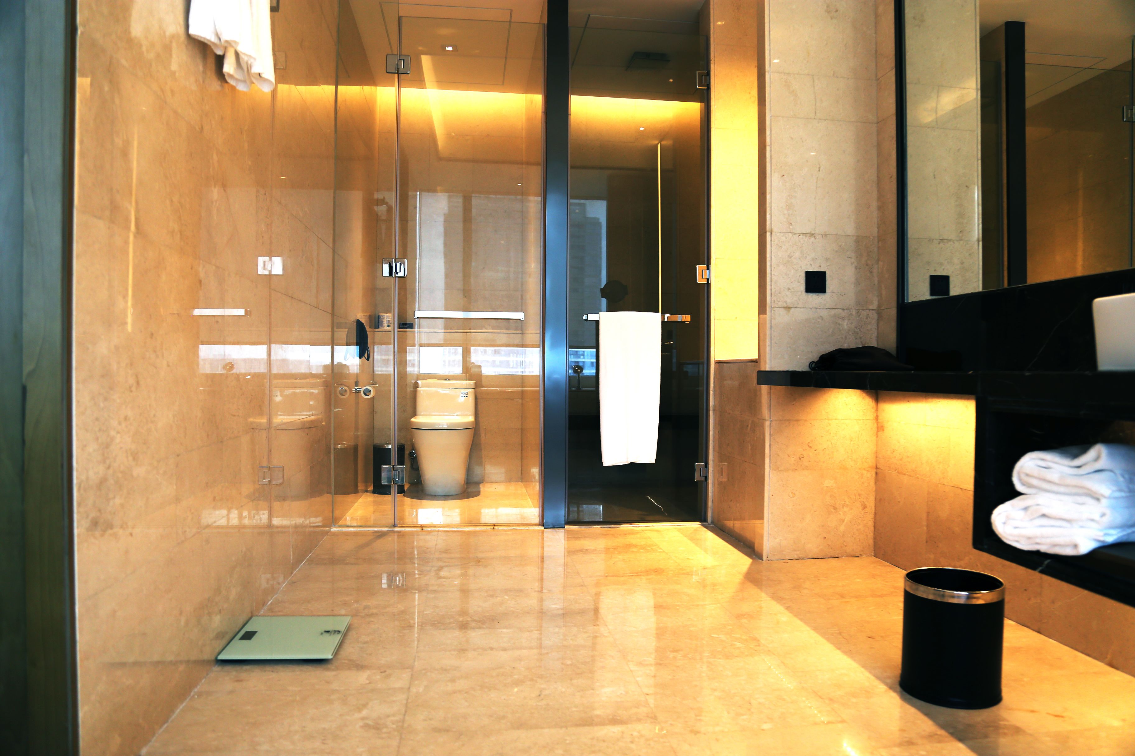 Un baño moderno con cabina de ducha de vidrio, inodoro y zona de lavamanos con toallero.