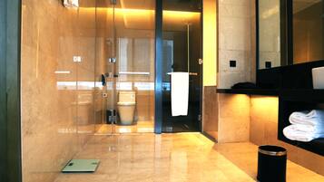 Un baño moderno con cabina de ducha de vidrio, inodoro y zona de lavamanos con toallero.