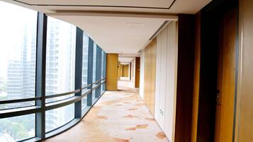 A corridor with large windows, wooden doors, and a patterned floor.