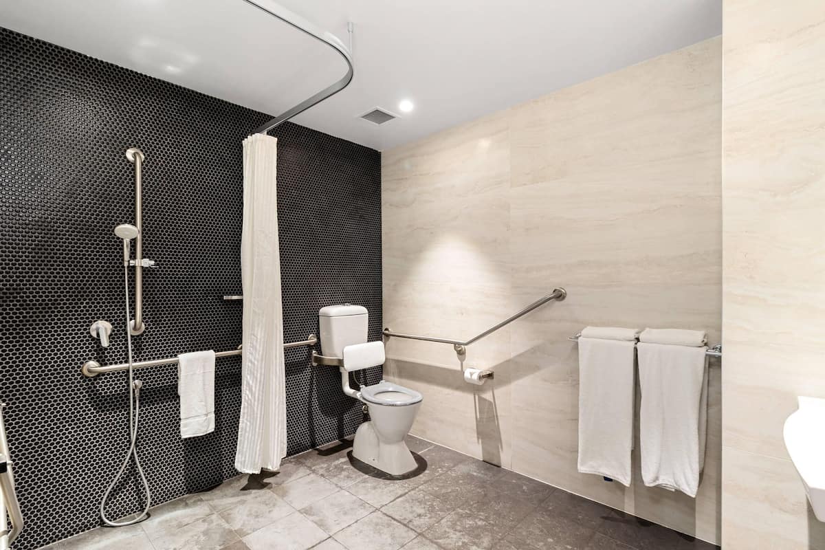 Een moderne badkamer met douche, toilet en handgrepen.