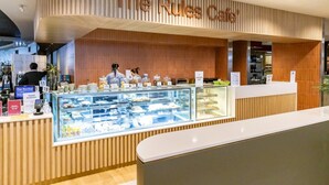 Ein Café namens 'The Rules Cafe' mit modernem Design, einer Theke und einer Vitrine mit verschiedenen Speisen.