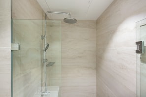 Une salle de bain moderne dotée d’une douche à parois de verre, d’un pommeau de douche à main et d’un robinet mural.