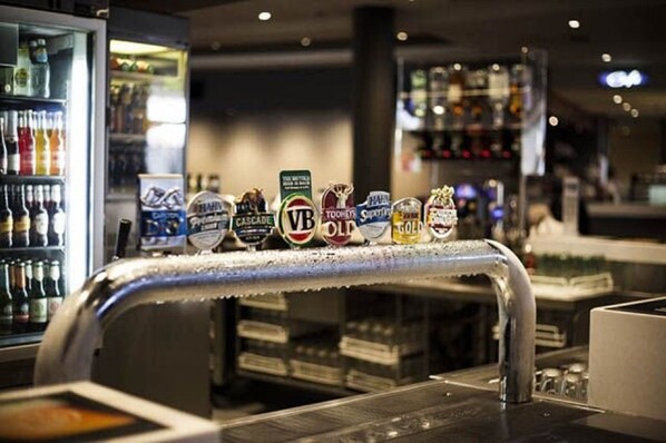 Een bar met een biertappunt en verschillende etiketten van bierflesjes.