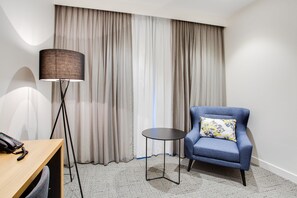 Une chambre d’hôtel équipée d’un bureau, d’une chaise, d’une lampe et offrant une vue sur les rideaux.