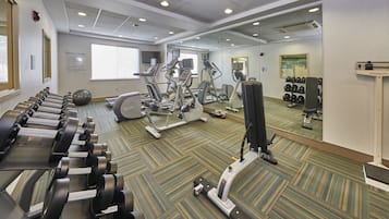 Un gimnasio con cintas de correr, elípticas y pesas sueltas.