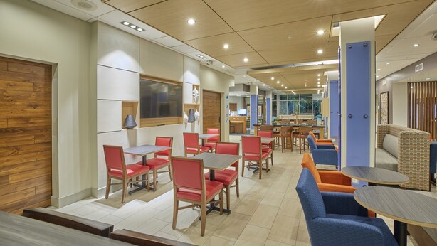 A modern dining area with wooden walls, red and blue chairs, and a central table.